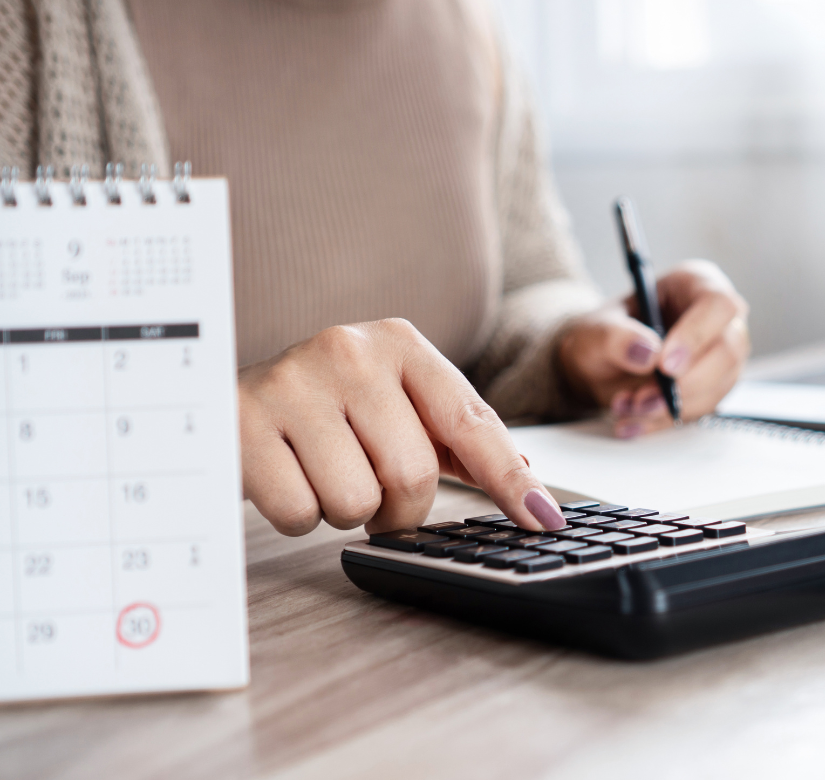 Kobieta notująca przy kalendarzu i kalkulatorze – monitorowanie terminów i wsparcie w windykacji należności.